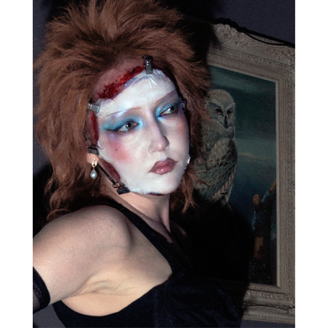 A women with spcial effects make-up, she looks like aan 80s rockstar , her face bloody mask