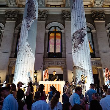Menschen h&ouml;ren bei Nacht einem DJ vor dem Nationaltheater zu